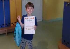 Chłopiec z dyplomem i nagrodą za udział w konkursie.